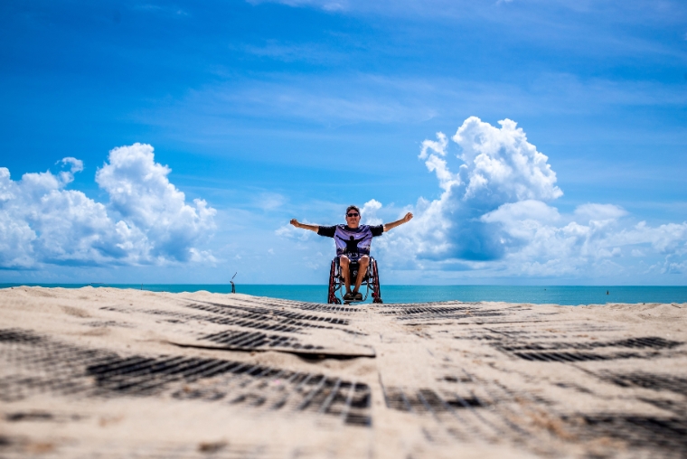 Man in rolstoel geniet van het strand tijdens een toegankelijke vakantie